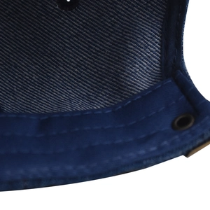 Detail shot of navy denim baseball cap inner edge with stitching and metal eyelet