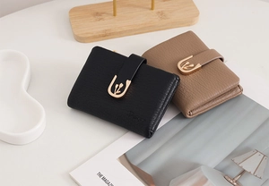 Close-up of pebble grain leather wallets with gold tulip buckles in black and brown
