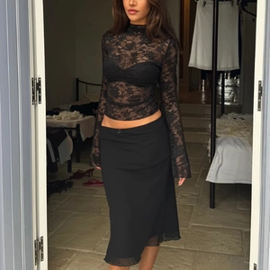 Détail du haut transparent en dentelle noire à manches longues avec coupe moulante sexy