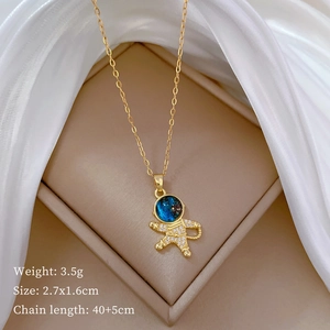 Macro view of gold titanium astronaut pendant with blue starry head and zircon stones
