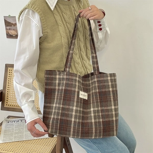 Close-up of retro plaid canvas tote bag with woven label and vintage grid pattern texture