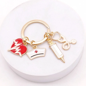 Macro detail of gold medical keychain with nurse hat, syringe and stethoscope charms