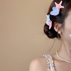Close-up of floral starfish hair clip with pearls worn by a model in a beach style