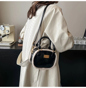 Close-up of black leather bag with cream plush trim and adjustable gold shoulder strap