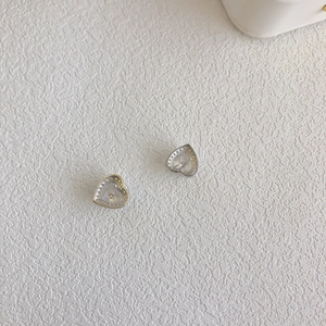 Macro shot of S925 sterling silver heart studs with clear AAA zirconia inlay on white