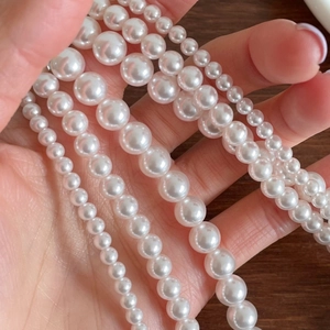 Multiple sizes of lustrous 925 silver pearl necklaces shown on hand with wooden background