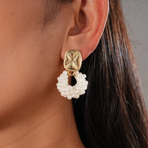 Vintage gold finish flower earrings set with faux pearls shown on a model's ear