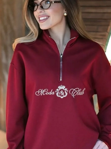 Detail of burgundy half-zip sweatshirt with white Moda Club logo and crown emblem