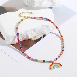 Detail of colorful beaded necklace with rainbow heart pendant on a white stone base
