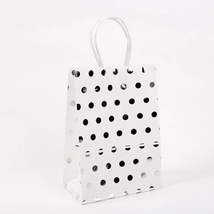 Detail of white kraft paper gift bag with silver polka dots and white rope handles