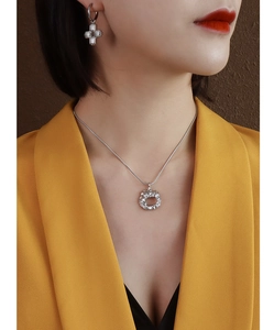 Detailed view of silver irregular pendant necklace and cross earrings on a female model