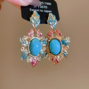 Detailed close-up of retro gold alloy earrings featuring turquoise stone and leaf enamel