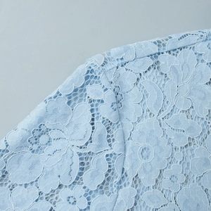 Detailed close-up of light blue floral lace fabric with intricate mesh patterns