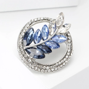 Close-up of a silver wheat brooch with clear rhinestones and blue crystals on white