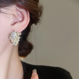 Detailed close-up of crystal leaf earrings with sparkling zircon stones on female model