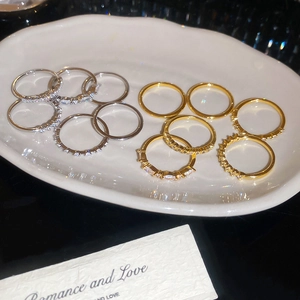 Detailed view of gold and silver geometric rings with sparkling zircon inlay on white plate