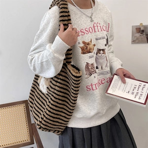 Detail of a plush striped tote bag with a cute cartoon dog motif and cat print sweatshirt