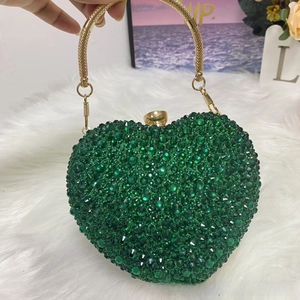 Macro detail of dark green rhinestone heart evening bag with woven gold handle