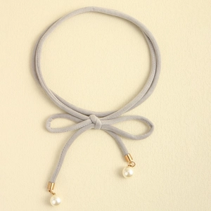 Detail of grey velvet ribbon choker with elegant bow, gold tips and white faux pearl charms
