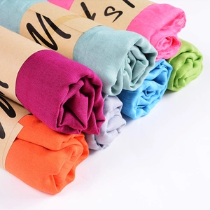 Multiple colors of pleated cotton linen scarves neatly arranged with paper sleeves