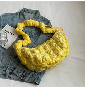 Detail of quilted bright yellow cloud tote bag on denim jacket with textured fabric