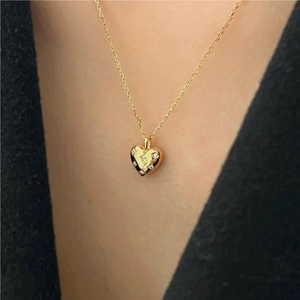Detailed view of a gold heart pendant necklace with micro-pave cubic zirconia on model