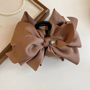 Macro detail of large brown satin bow hair claw clip with a centered faceted gemstone