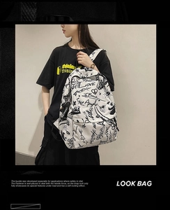 Detail of white backpack with black graffiti print and adjustable straps on a model