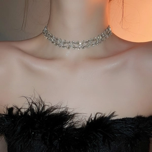 Close-up of a silver multi-row braided choker necklace with sparkling crystals on a model