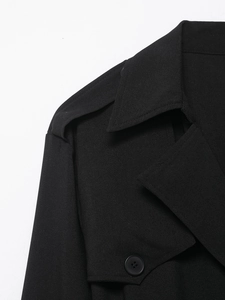 Detail shot of black trench dress collar with epaulettes and textured woven fabric