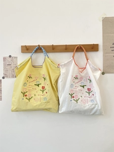 Detail of floral embroidery on canvas tote bag with stylish checkered woven handles