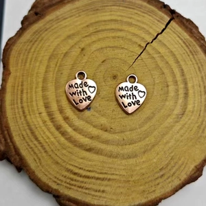 Vista detallada de colgantes de corazón en aleación con grabado Made with Love en madera