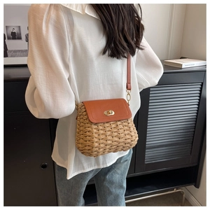 Detail of handmade straw crossbody bag with brown leather flap on a model