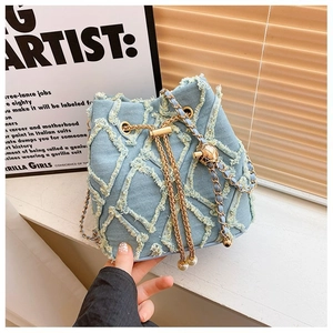 Detail of light blue denim bucket bag with gold chain, pearls and frayed fringe accents