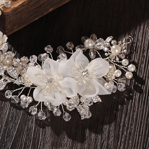 Detailed shot of bridal hair comb with white fabric flowers, pearls and crystal beads