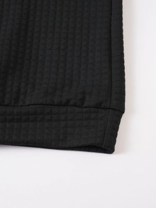 Macro view of black waffle knit texture and ribbed cuff on a men's hoodie sleeve