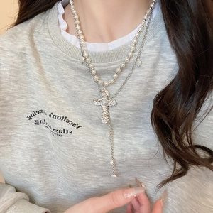 Détail du collier double rang avec pendentif croix en perles et texture chaîne argent