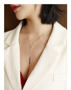 Model wearing a minimalist V-shaped silver necklace with a long vertical bar pendant