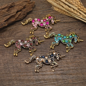 Detailed macro view of four vintage gold unicorn brooches with colorful rhinestones on wood