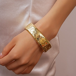 Detailed view of vintage gold engraved bangle with elegant floral patterns on a wrist