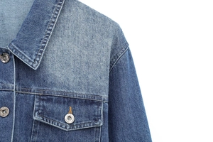 Detail of denim jacket collar and shoulder with washed texture and metal buttons