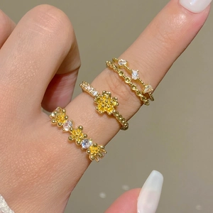 Detail of three gold rings set with yellow and white zircons in floral vintage styles