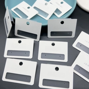 Macro view of white rectangular jewelry display cards with hanging holes on black background