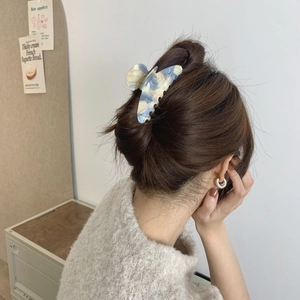 Close-up of marble-patterned acetate hair claw clip securing a low bun hairstyle