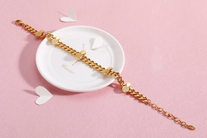 Detailed close-up of golden pineapple charms on a Cuban link bracelet with lobster clasp
