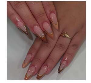 Detail of almond-shaped nails with French Maillard brown tones and gold glitter edges