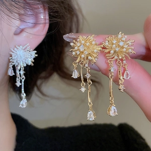 Detail of gold starburst earrings with white pearls and long tassel drop zircons