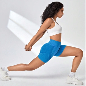 Women's blue seamless high-waist yoga shorts and white tank top in a side stretching pose