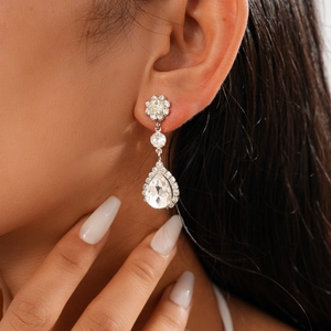 Macro detail of elegant silver pear-shaped crystal drop earrings on a model's ear