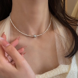 Close-up of minimalist silver necklace with elegant gray pearl pendant on neck